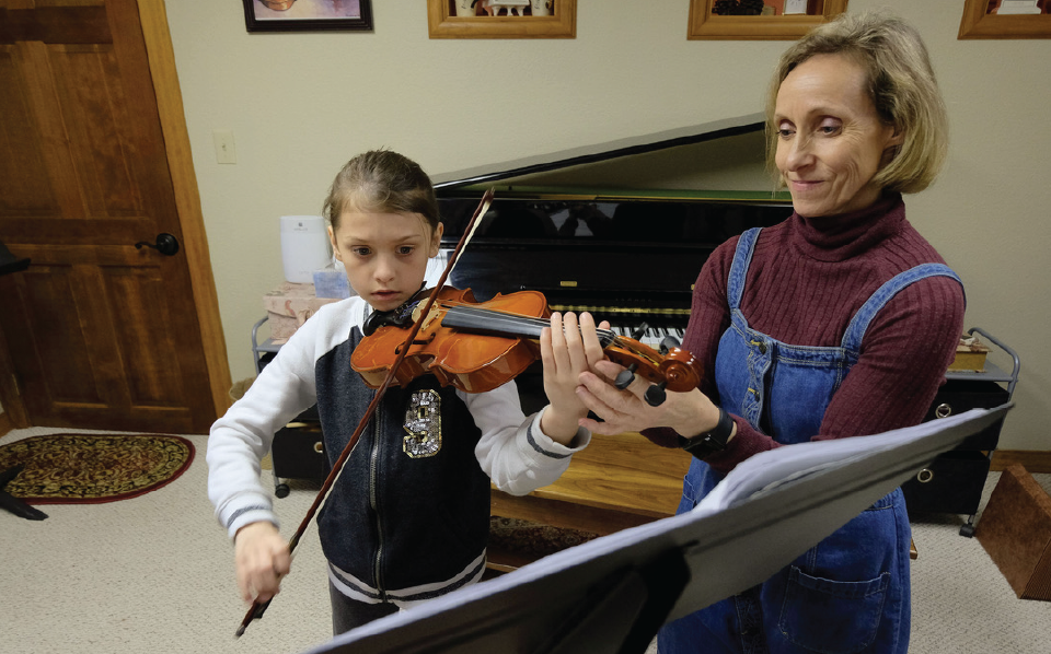 Kasia teaching young girl how to play violin